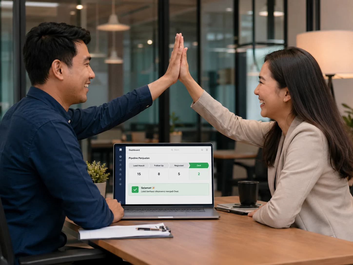 Sales team 2 orang tersenyum high-five di depan laptop pipeline deal